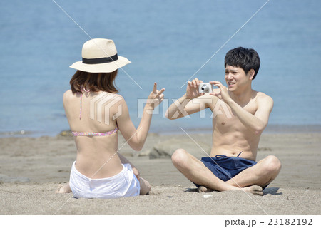 海で写真を撮る若いカップル 海で写真を撮る若いカップル 23182192