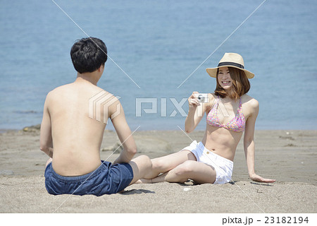 海で写真を撮る若いカップル 海で写真を撮る若いカップル 23182194