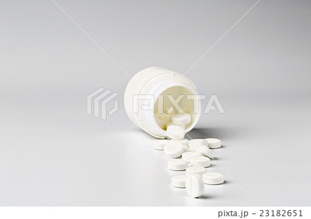 White plastic pill bottle and heap of round pills White plastic pill bottle and heap of round pills 23182651