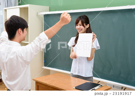 満点のテストを返却する女性教師ガッツポーズで喜ぶ男子生徒 23191917