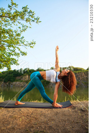 Young woman is practicing yoga near river 23210330