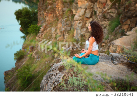 Young woman is practicing yoga near river Young woman is practicing yoga near river 23210641