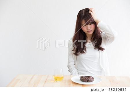 ドーナッツを我慢する女性・白バック 23210655