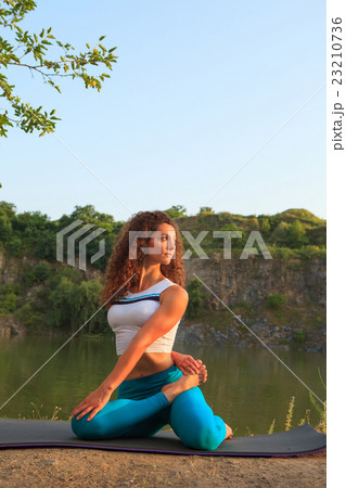 Young woman is practicing yoga near river 23210736