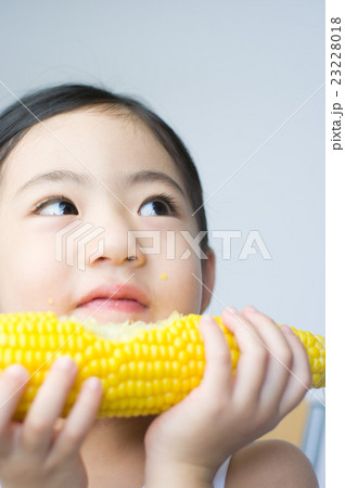 とうもろこしを食べている女の子の写真素材