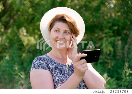 woman in hat with cell phone outside woman in hat with cell phone outside 23233793