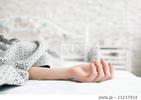 Hand of sleeping in bed covered woman closeup Hand of sleeping in bed covered woman closeup 23237918