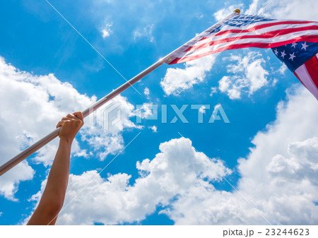 American flag with stars and stripes hold with hands against blue sky . American flag with stars and stripes hold with hands against blue sky . 23244623