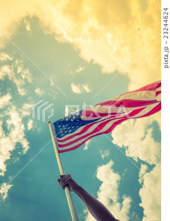American flag with stars and stripes hold with hands against blue sky ( Filtered image processed vintage effect ) American flag with stars and stripes hold with hands against blue sky ( Filtered image processed vintage effect ) 23244624