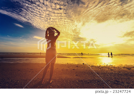 young woman standing on sand and looking to a sky 23247724