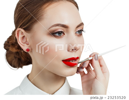 Young woman applying lipstick with an applicator Young woman applying lipstick with an applicator 23253520