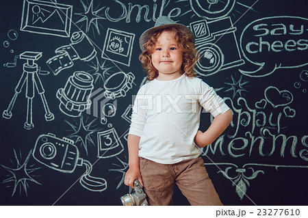Little boy with a camera is standing on a black 23277610