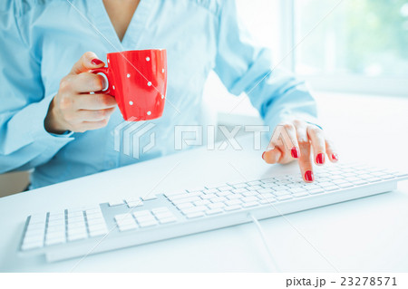 Woman office worker typing on the keyboard and drinking coffee 23278571