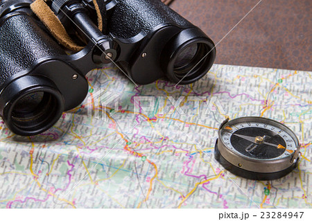Binoculars and compass on map. 23284947
