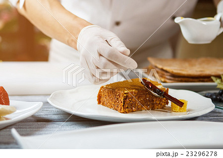 Hand with spoon beside cake. 23296278
