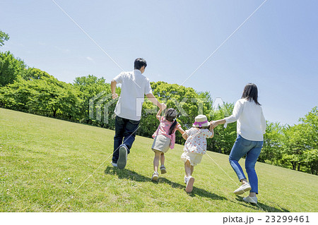 新緑の公園を歩く4人家族の後ろ姿の写真素材