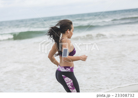 Young female runner jogging on the beach Young female runner jogging on the beach 23308732