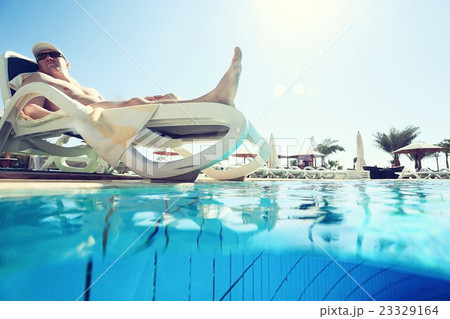 man sunbathing on a sun lounger by the pool 23329164