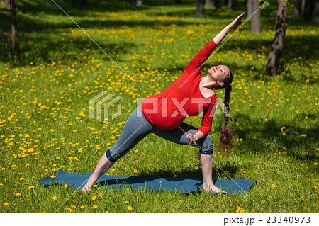 Pregnant woman doing asana Utthita parsvakonasana Pregnant woman doing asana Utthita parsvakonasana 23340973