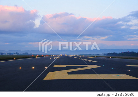 滑走路の誘導灯と雲と山の写真素材