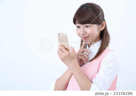 スマホをするエプロン姿の女性 スマホをするエプロン姿の女性 23356286