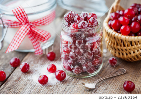 Cranberries with sugar in jar, basket with berries 23360164