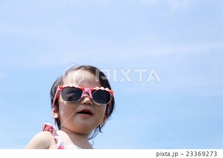 サングラス 赤ちゃん ベビー 乳児 女の子 1才 1歳 グラサン バカンス リゾート 青空バック の写真素材