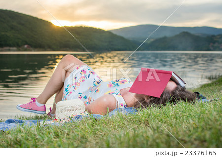 Woman sleeping with a book by the lake. 23376165