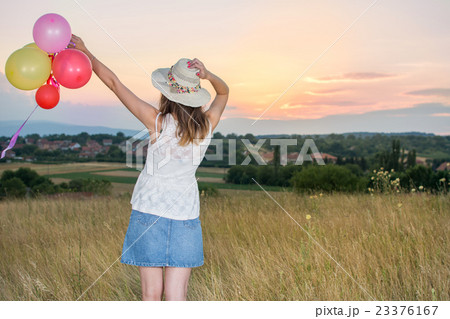 Young woman holding balloons looking at sunset 23376167
