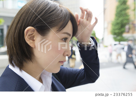 ビジネスウーマン 外 ビルの窓ガラスをみて身だしなみを整える 横顔 丸の内 通りの写真素材