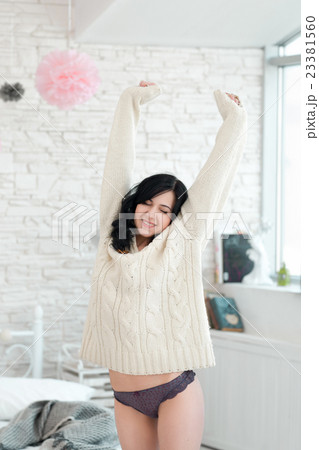 Woman in white pullover stretching in bedroom Woman in white pullover stretching in bedroom 23381560