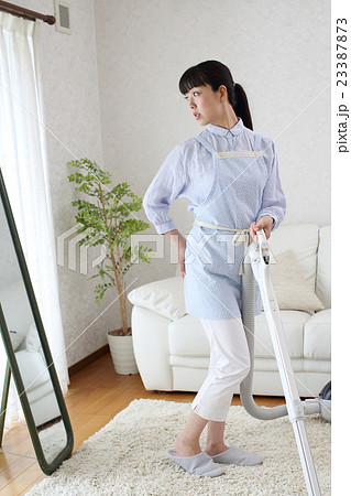 掃除をしながら体型の衰えに悩む主婦 23387873