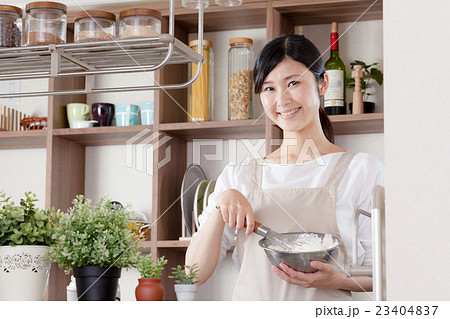 エプロンを着た女性、泡立て器、ボウル 23404837