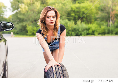 Woman changing tire on a road Woman changing tire on a road 23405641