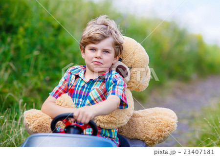 Little kid boy driving big toy car with a bear Little kid boy driving big toy car with a bear 23407181