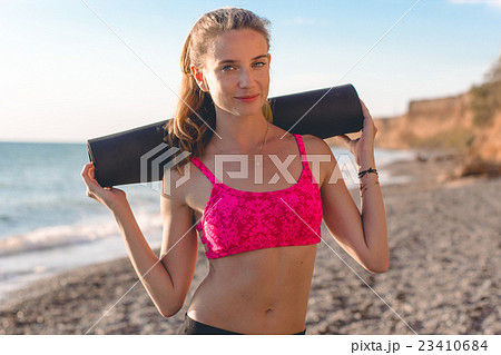 Young woman with mat on the beach Young woman with mat on the beach 23410684