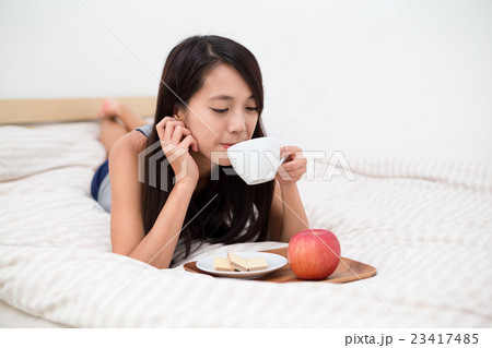 Woman lying down and having breakfast 23417485