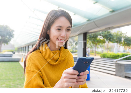 Asian Young Woman play the game though mobile phone 23417726