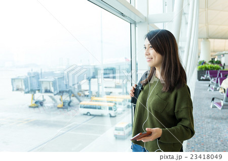 Woman listen to song with cellphone at airport 23418049
