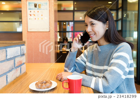 Woman talk to cellphone and enjoy her breakfast in coffee shop 23418299