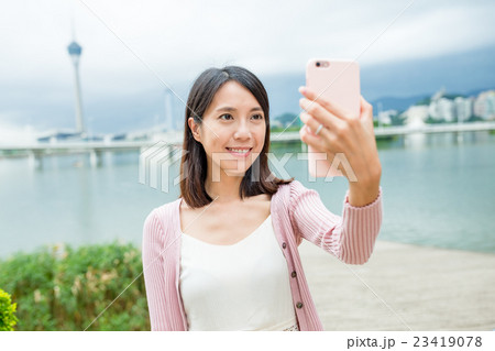 Woman taking selfie by cellphone in Macau Woman taking selfie by cellphone in Macau 23419078