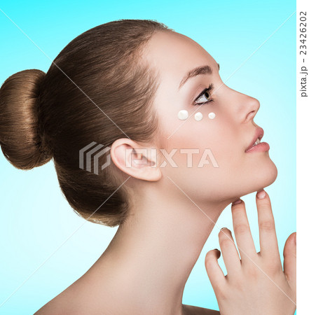 Beautiful model applying cream on face 23426202