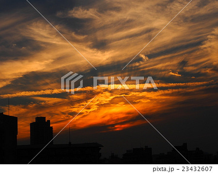 ビル街に沈む鮮烈なオレンジ色の夕焼けの写真素材