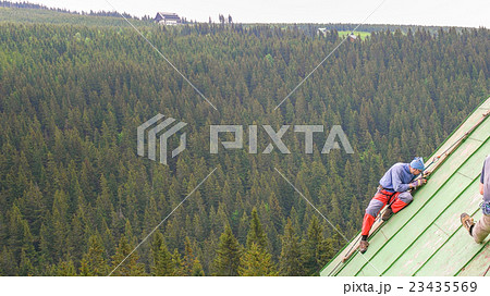 Man Working on the Roof, Scraping the Paint 23435569