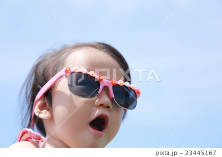サングラス 赤ちゃん ベビー 乳児 女の子 1才 1歳 グラサン バカンス リゾート 青空バック の写真素材
