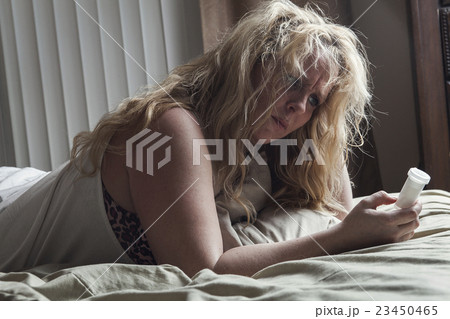 A sad woman taking medication on bed. A sad woman taking medication on bed. 23450465