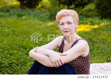 Portrait of middle aged woman smiling in the park Portrait of middle aged woman smiling in the park 23452435
