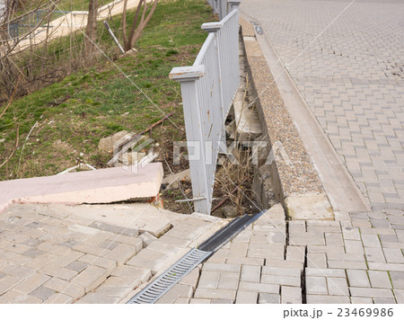 The destruction of the pedestrian walkway of stone tiles, and the brittle behavior of the fence 23469986
