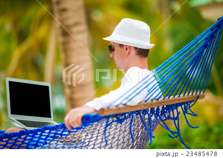Young man with laptop at hammock on tropical Young man with laptop at hammock on tropical 23485478