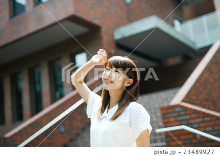 建物の外で空を見る女性 23489927